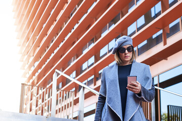 Fashionable woman using smartphone in city setting