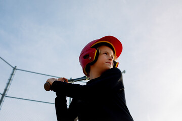 Young boy up to bat in a red helmet, focused and poised