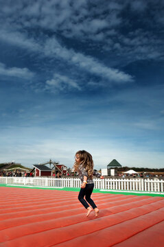 Happy little girl jumping on inflatable toy under blue skies