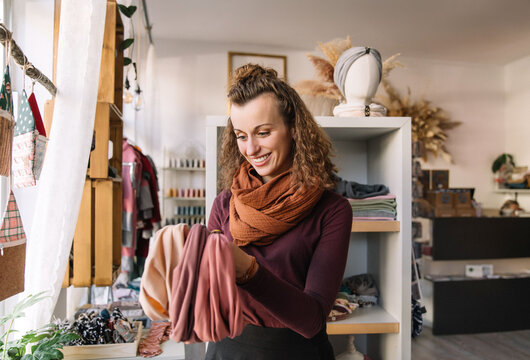 Woman Happily Exploring Fabric Choices in a Boutique Craft Shop