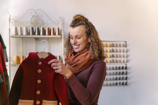 Cheerful Woman Admiring a Handmade Jacket in a Creative Boutique