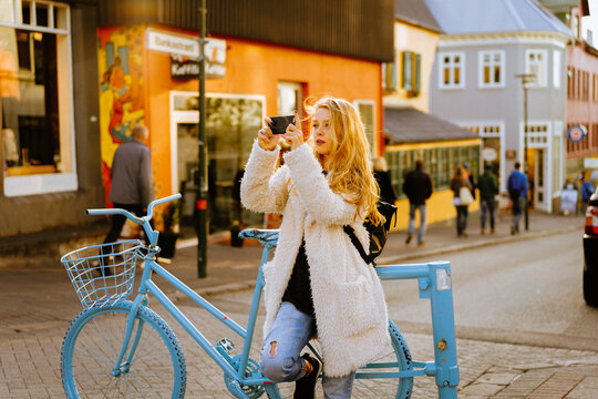 Smiling woman using mobile phone on the street.