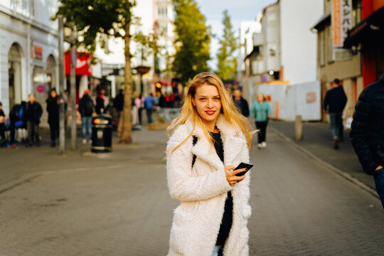Smiling woman using mobile phone on the street.