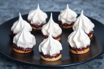 cookies with white meringue, pink cream on biscuit layer and black plate background