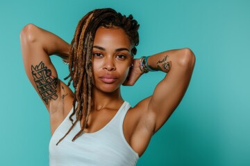 Determined woman with dreadlocks striking a pose, flexing her biceps for a commercial photo on a solid color background