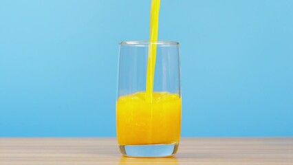Pouring Fresh Orange Juice into Glass on table.