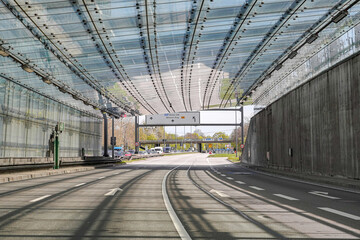 A four-lane road exiting the tunnel into the city. Automotive industry.