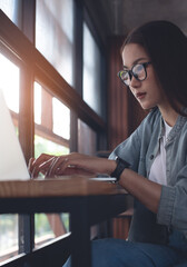 Asian woman working on laptop computer at coffee shop. Student online studying, surfing the...