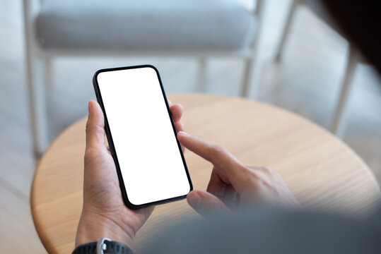 Mockup, using cell phone in a cafe coffee shop. Woman holding using smartphone with blank screen for display your graphic ads, mobile app. close-up 