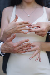 Male and female hands as silhouettes hold wedding rings facing each other. The bride and groom put their wedding rings against the sky. Weddings and gold wedding rings.