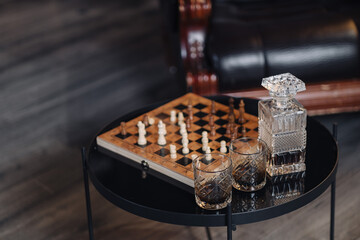 chessboard with chess and three cigars in the center on a wooden background