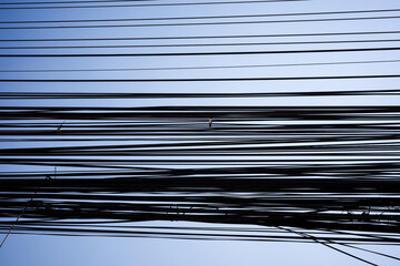 electrical wires cluttered on a blue sky background