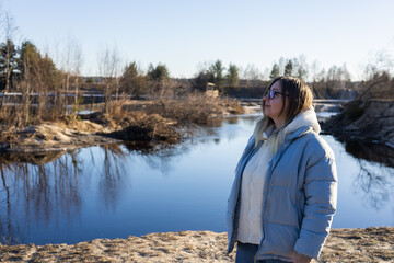 Pensive women stands on the river bank and admires the beautiful view. Portrait of a woman on the...