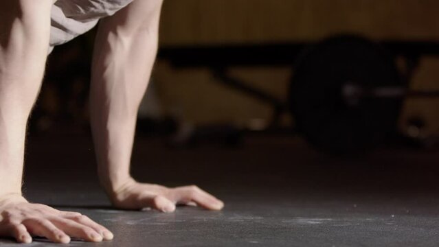 Male Swedish athlete do strict push ups in gym, low angle side closeup