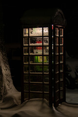 An English telephone booth illuminated from the inside by soft evening light on a snowy street in Myoko, Japan