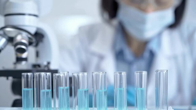 Test tubes with a blurred scientist in a lab coat in the background