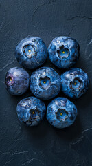 A cluster of dewy blueberries, each with a perfect sheen, arranged in a tight circle and viewed from above, creating a natural mandala on a navy background 