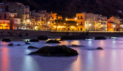 evening or night landscape of sea gulf with calm water and beautiful evening town highlighted with...