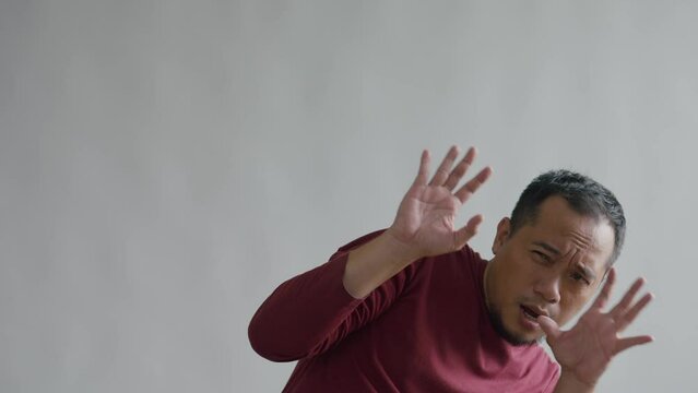 Frightened Asian Man Feeling Afraid And Back Away Isolated On Gray Background.