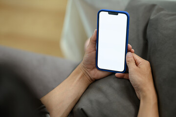 Closeup shot of man lying on sofa holding smartphone with blank empty screen