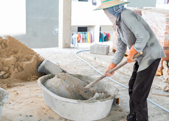 Worker using hoe to mixing sand and cement manually.