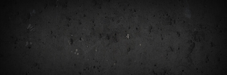 Texture of old concrete wall. Rough dark gray concrete surface with spots, cracks, noise and grain. Dark wide panoramic background for grunge style design. Shaded vintage texture with vignette.