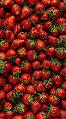A pile of strawberries with green leaves.