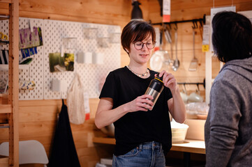 In a homely and rustic kitchen setting, a young adult with glasses is pictured using a thermal...