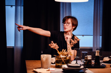 This striking image captures a young adult gesturing actively at a dinner table, potentially giving...