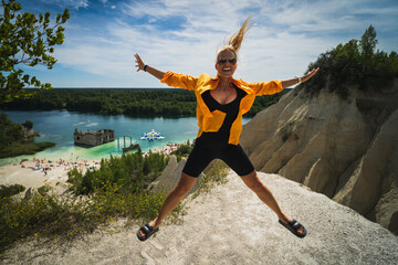 Athletic girl jumping in nature in Estonia on the Rummu quarry hill on a summer day.
