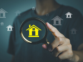 Search for a house. Buyer or renter holding a magnifying glass searches for a house, residential...