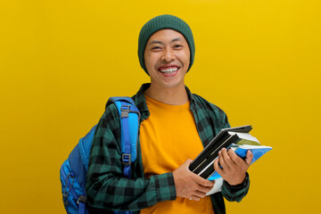 A confident young Asian student, dressed in a beanie hat and casual shirt and carrying a backpack,...