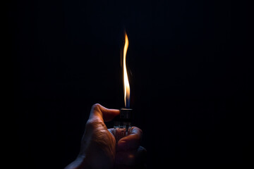 Hand with lighter igniting sparks on dark background. Remaining energy concept Let's help each...