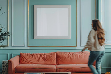 indoor setting with a woman passing by a turquoise wall and peach sofa, blank white frame