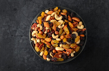 Mix of dried nuts and raisins on a black background.