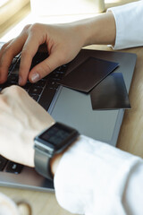 close up of a person typing on a laptop. Business cards on the notebook
