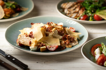Caesar salad with chicken breast, tomatoes and sliced parmesan cheese. Meals are served on the table in the restaurant. Restaurant menu