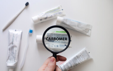 Dangerous toothpaste ingredient carbomer. Checking the composition of toothpaste with a magnifying...