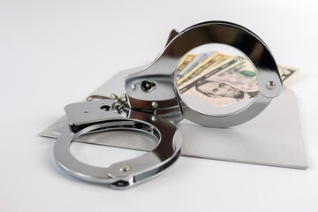 Handcuffs, dollars and an envelope. The concept of financial dependence.