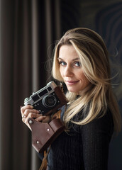 pretty girl photographer with a camera in her hand on a dark background
