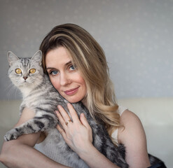 portrait of a pretty girl with a gray cat in her hands at home.