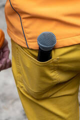 Microphone in the back pocket of yellow trousers, microphone for karaoke, event host, party, singer