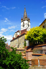 View of the bell tower of St. Mary's Church from the old town in Sibiu, Romania. Sights of Transylvania. Cityscape of a medieval European town on a sunny day.