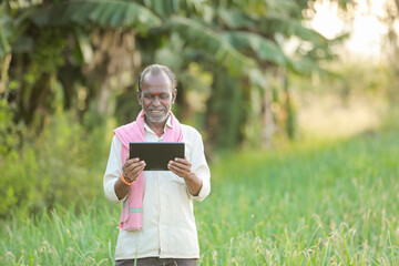 Indian farm worker holding tablet in onion farm