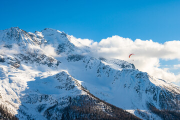 Paraglider flying in mountains during winter season, Loetschental valley, Switzerland
