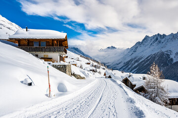 Fototapeta na wymiar Winter snowy road with typical wooden houses in alpine village, Loetschental valley, Switzerland