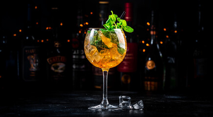 Summer refreshing cocktail drink with cognac, liqueur, sparkling wine with ice and mint in wine glass, dark background
