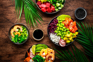 Poke bowls for balanced diet with vegetables, legumes, seafood, avocado and rice, wood table background, top view