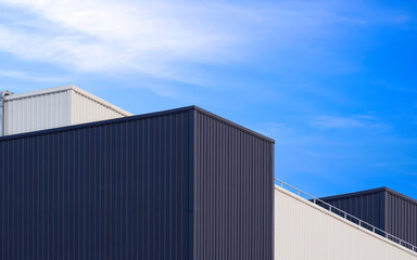 Black and white modern geometric aluminium factory buildings against blue sky background, Low angle...