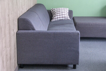 The location of a regular sofa in the corner of the room, an additional ottoman to the sofa as part